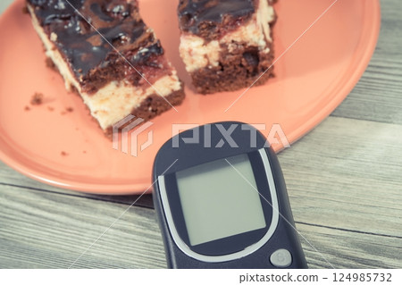 Glucose meter for measuring sugar level and fresh cheesecake with cherries and chocolate Glucose meter for measuring sugar level and fresh cheesecake with cherries and chocolate 124985732