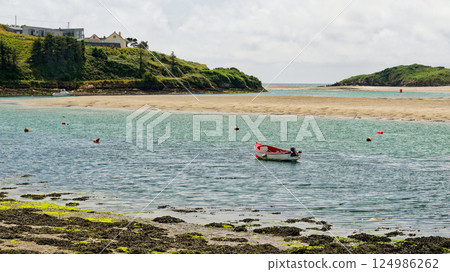 A serene afternoon at Middle Ring Bay Beach, where a small boat glides through the clear waters, surrounded by lush greenery and sandy shores. A serene afternoon at Middle Ring Bay Beach, where a small boat glides through the clear waters, surrounded by lush greenery and sandy shores. 124986262