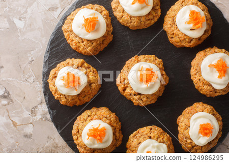 Diet gluten free carrot oatmeal cookies with cream cheese icing close-up on a plate. Horizontal top view 124986295