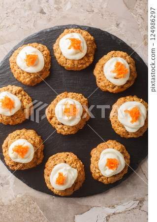 Delicious carrot cake cookies with cream cheese frosting are a must-have Easter dessert close up on the plate. Vertical top view 124986297