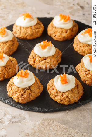 Delicious carrot cake cookies with cream cheese frosting are a must-have Easter dessert close up on the plate. Vertical 124986303