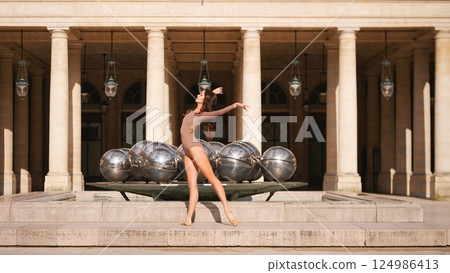 Ballet dancer en pointe in front of Palais Royal fountain sculpture 124986413