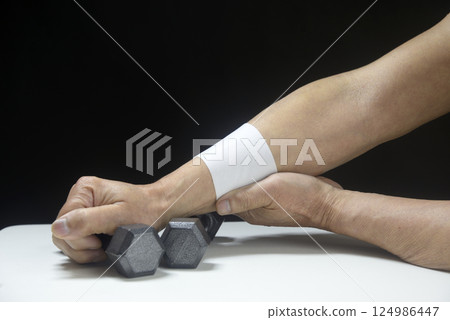 An old man's arm doing rehabilitation with a dumbbell and a compress 124986447