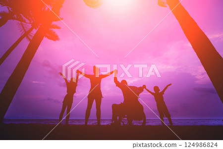 Disabled man in a wheelchair with his family on the beach. Silhouettes at sunset Disabled man in a wheelchair with his family on the beach. Silhouettes at sunset 124986824