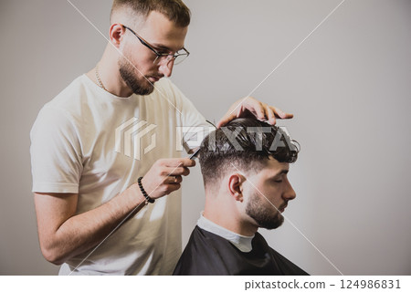 Young man with trendy haircut at barber shop. Young man with trendy haircut at barber shop. 124986831