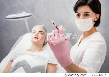 The doctor cosmetologist makes the facial injections procedure. The doctor cosmetologist makes the facial injections procedure. 124986854