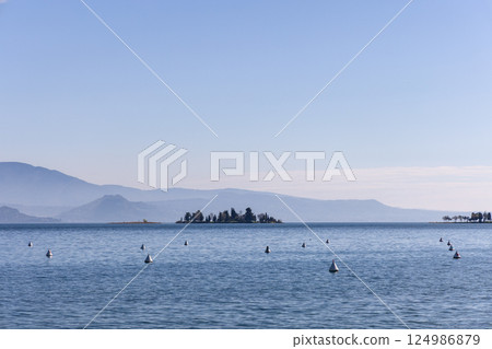 Peaceful spring morning on Lake Garda with distant San Biagio island 124986879