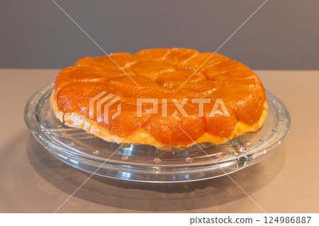 Freshly baked Tarte Tatin placed on a glass plate, showing glossy caramelized apple topping Freshly baked Tarte Tatin placed on a glass plate, showing glossy caramelized apple topping 124986887