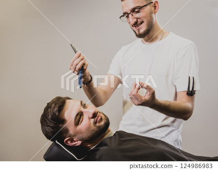Young man with trendy haircut at barber shop.  124986983