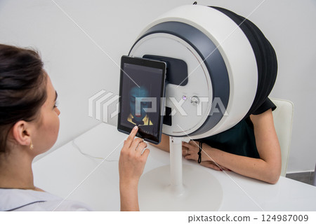 Face skin analyze system. Cosmetologist analyzing woman face.  124987009
