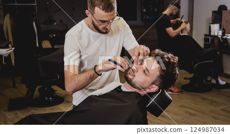 Young man with trendy haircut at barber shop.  124987034