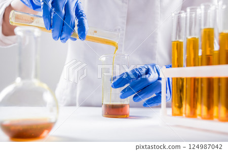Scientist pouring organic oil. Beauty and cosmetics sciences. Scientist pouring organic oil. Beauty and cosmetics sciences. 124987042
