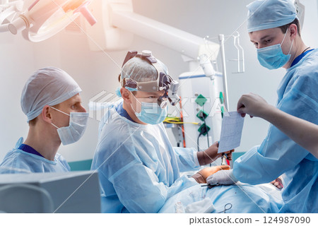 Spinal surgery. Group of surgeons in operating room with surgery equipment. Spinal surgery. Group of surgeons in operating room with surgery equipment. 124987090