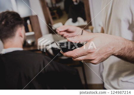 Young man with trendy haircut at barber shop.  124987214