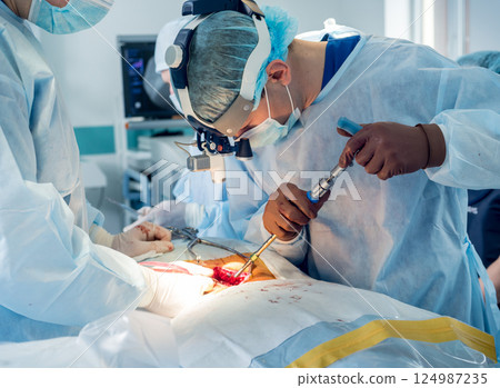 Spinal surgery. Group of surgeons in operating room with surgery equipment.  124987235