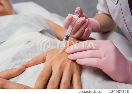 The doctor cosmetologist makes the arms injections procedure. The doctor cosmetologist makes the arms injections procedure. 124987258