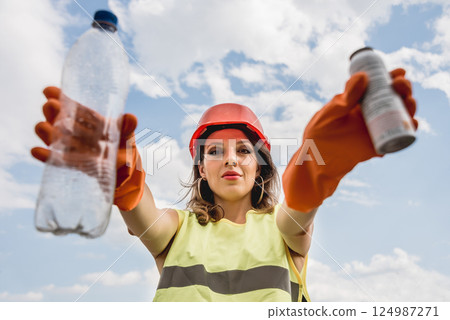 Woman volunteer helps clean the field of plastic garbage. 124987271