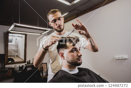 Young man with trendy haircut at barber shop. Young man with trendy haircut at barber shop. 124987272