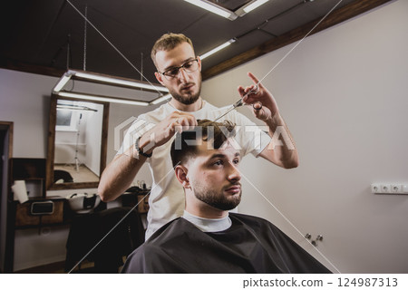 Young man with trendy haircut at barber shop.  124987313