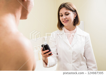 The doctor connects an insulin pump to a patient with diabetes. 124987395