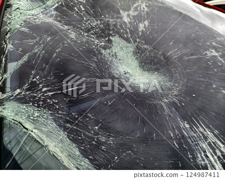 Shattered and broken windshield on a bright red car showcasing the damage to its glass surface 124987411