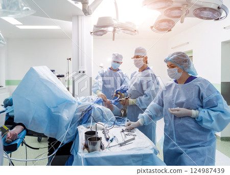 Arthroscope surgery. Orthopedic surgeons in teamwork in the operating room Arthroscope surgery. Orthopedic surgeons in teamwork in the operating room 124987439