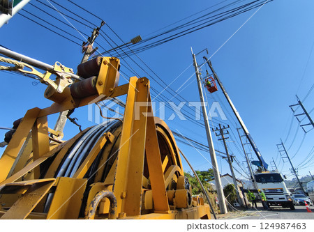 Installation of high-voltage electric wires on new poles along the road 124987463