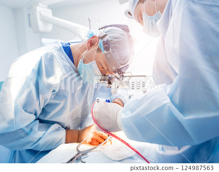 Spinal surgery. Group of surgeons in operating room with surgery equipment. 124987563