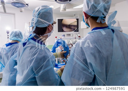 Arthroscope surgery. Orthopedic surgeons in teamwork in the operating room  124987591