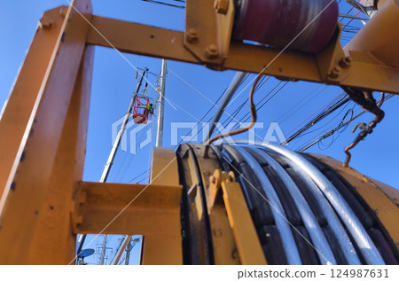 Installation of high-voltage electric wires on new poles along the road 124987631