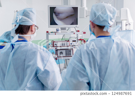 Arthroscope surgery. Orthopedic surgeons in teamwork in the operating room Arthroscope surgery. Orthopedic surgeons in teamwork in the operating room 124987691