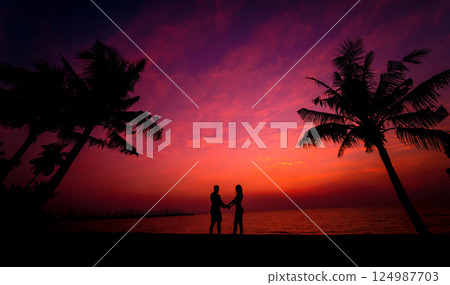 Silhouette of couple on tropical beach during sunset Silhouette of couple on tropical beach during sunset 124987703