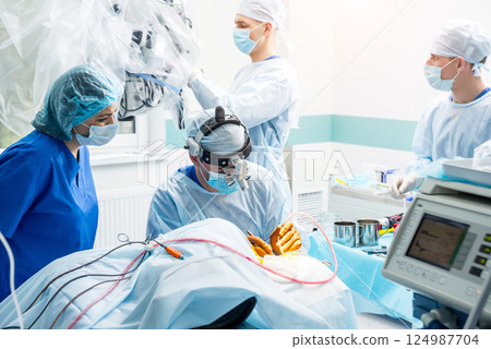 Brain surgery. Group of surgeons in operating room with surgery equipment. Brain surgery. Group of surgeons in operating room with surgery equipment. 124987704