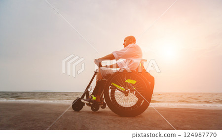 Disabled man in a wheelchair on the beach. Disabled man in a wheelchair on the beach. 124987770