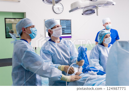Arthroscope surgery. Orthopedic surgeons in teamwork in the operating room Arthroscope surgery. Orthopedic surgeons in teamwork in the operating room 124987771