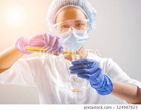 Scientist pouring organic oil. Beauty and cosmetics sciences. Scientist pouring organic oil. Beauty and cosmetics sciences. 124987823