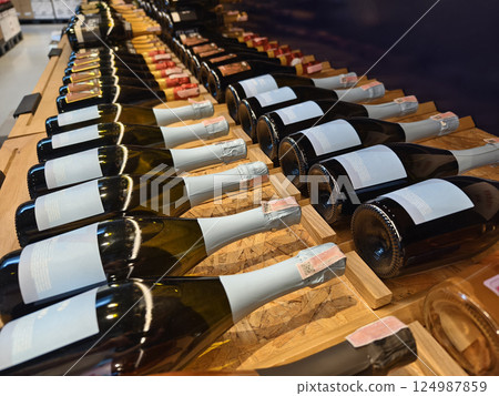 A variety of bottles of champagne are elegantly lined up on a wooden shelf A variety of bottles of champagne are elegantly lined up on a wooden shelf 124987859