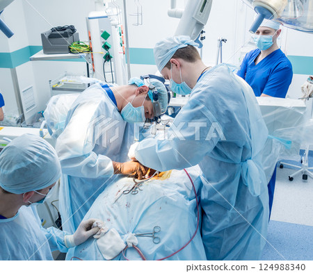 Spinal surgery. Group of surgeons in operating room with surgery equipment.  124988340