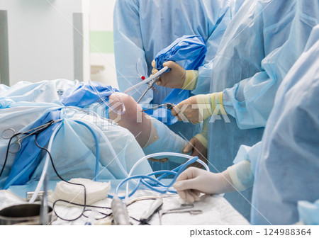 Arthroscope surgery. Orthopedic surgeons in teamwork in the operating room Arthroscope surgery. Orthopedic surgeons in teamwork in the operating room 124988364