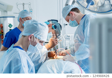 Spinal surgery. Group of surgeons in operating room with surgery equipment.  124988426