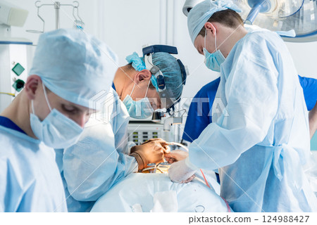 Spinal surgery. Group of surgeons in operating room with surgery equipment.  124988427