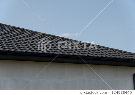 New roof installation features modern tiles on a residential home with a cloudy sky in the background, highlighting the construction work New roof installation features modern tiles on a residential home with a cloudy sky in the background, highlighting the construction work 124988440