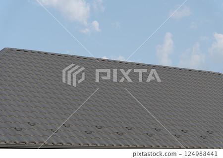 New tiles are being added to a rooftop, showcasing the roofing process at a construction site during daylight hours 124988441