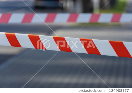 Brightly colored barrier tape restricts entry to a section of the street in a busy city, ensuring safety during an outdoor event 124988577