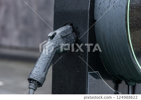 A charging station in wet conditions highlights the advancement of electric vehicle technology, emphasizing eco-friendly transportation options 124988622