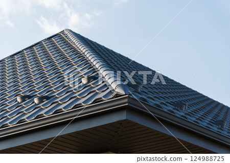 Bright sunshine illuminates the well-crafted roof with intricate tile patterns, standing out against a serene blue backdrop Bright sunshine illuminates the well-crafted roof with intricate tile patterns, standing out against a serene blue backdrop 124988725
