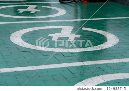 Green pavement features marked parking spaces with white symbols, indicating a designated area for specific vehicles in a busy urban environment Green pavement features marked parking spaces with white symbols, indicating a designated area for specific vehicles in a busy urban environment 124988745