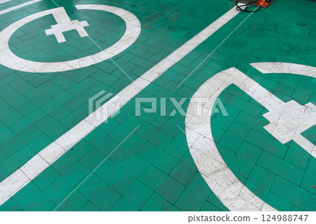 Clear markings on a green parking area illustrate designated spots for electric vehicles and bicycles, promoting eco-friendly transport options Clear markings on a green parking area illustrate designated spots for electric vehicles and bicycles, promoting eco-friendly transport options 124988747