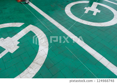 Clear markings on a green parking area designate spaces for electric vehicles and bicycles, promoting eco-friendly transportation options Clear markings on a green parking area designate spaces for electric vehicles and bicycles, promoting eco-friendly transportation options 124988748