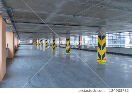 Spacious parking structure features minimal vehicles and marked columns, showcasing clean lines and industrial architecture 124988782